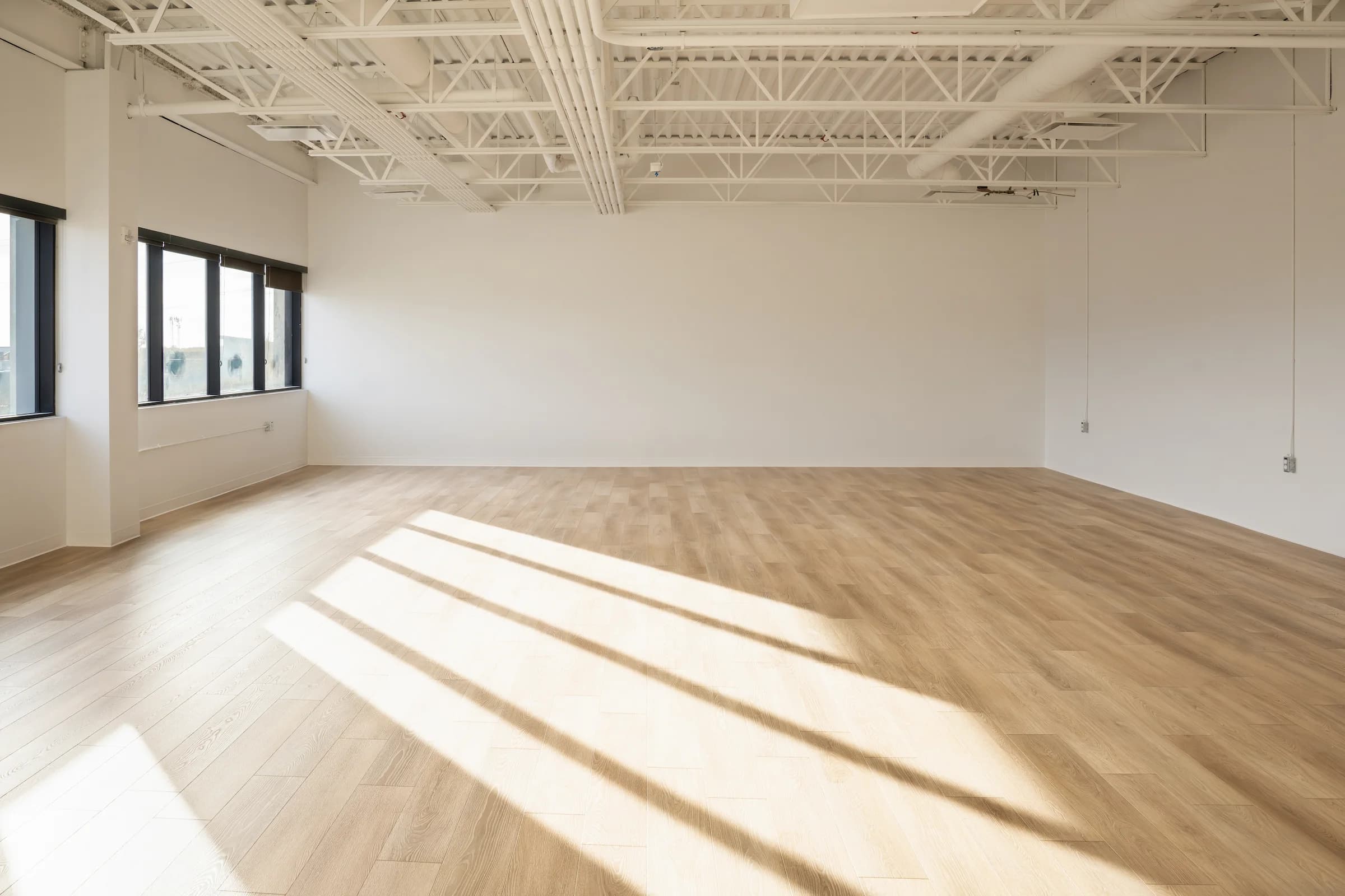 Open studio with light wood-look flooring and exposed ceiling